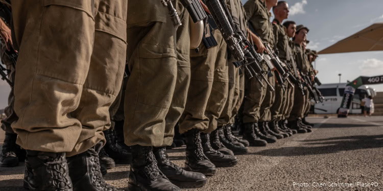 Military personnel standing in formation with rifles during a daytime outdoor event.