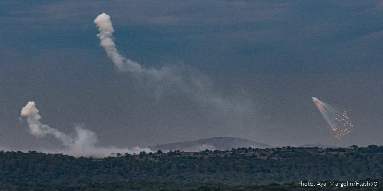 Aid distribution in Israel showing relief efforts amid ongoing conflict, with smoke and explosions in the background.
