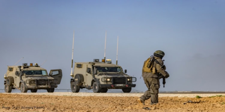 Military personnel and vehicles in a desert environment promoting peace and security efforts by IFCJ.