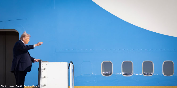 Donald Trump, former U.S. president, boarding an airplane with a blue exterior, waving to the crowd, during a public appearance or event.