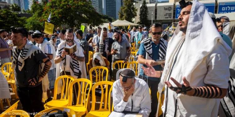 Former hostage Bar Kupershtein and dozens of Jewish men lay tefillin at Hostage Square in Tel Aviv, October 31, 2025