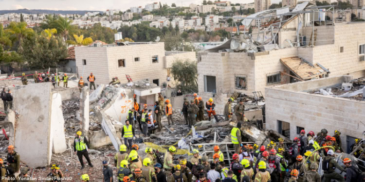 Emergency responders and volunteers assist in rescue operations at a collapsed building site after a disaster. The scene shows damaged structures, rescue teams, and affected residents in an urban envi.
