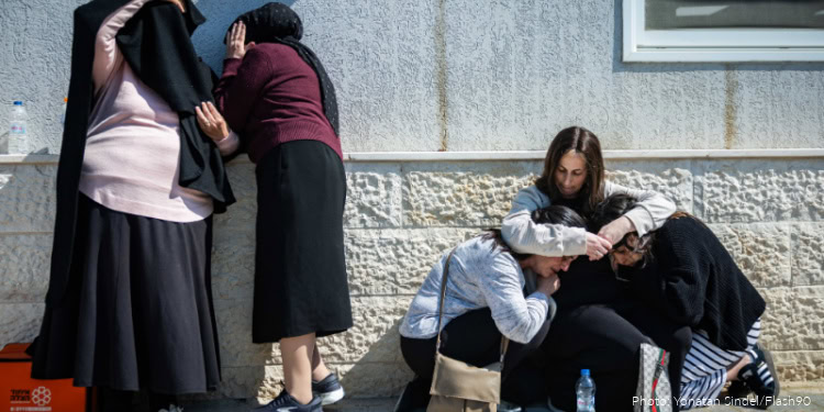 Volunteers providing support and comfort to refugees and displaced individuals outside a building, demonstrating compassion and aid in a humanitarian effort.