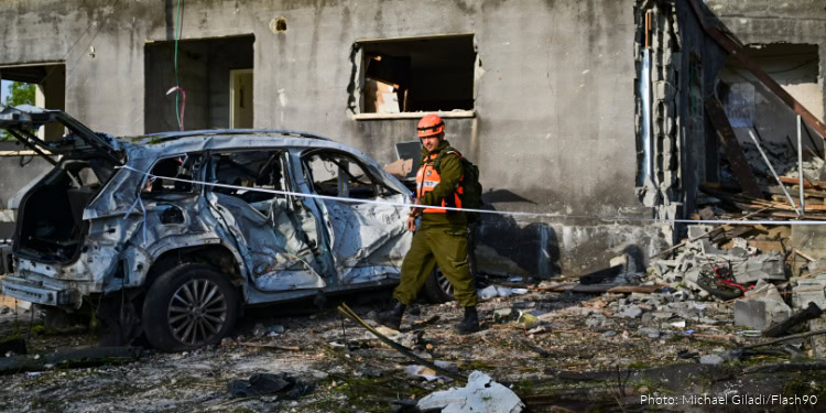 Emergency responder inspecting a damaged vehicle after a fire or explosion.