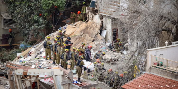 Firefighters and rescue personnel work amidst debris at the Haifa attack site, recovering bodies and searching for survivors after the devastating incident.