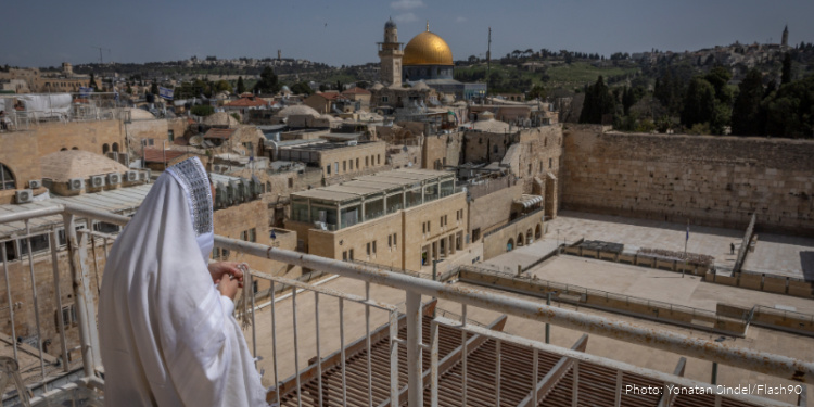 Jews pray on the rooftop of an apartment overlooking the Western Wall plaza in Jerusalem’s Old City during the Passover holiday, as the plaza remains closed for prayer due to the ongoing war, April 6, 2026. Photo by Yonatan Sindel/Flash90