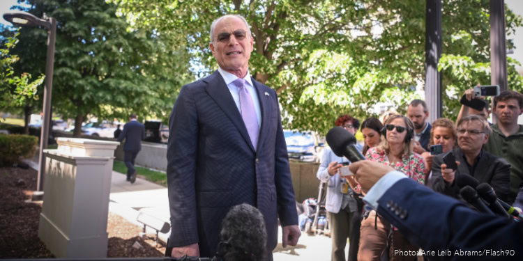Israeli official announces a 10-day ceasefire amid ongoing conflict, surrounded by journalists and supporters in a park setting.