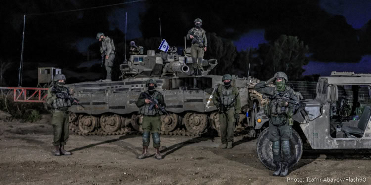 Israeli Defense Forces soldiers dismantling explosives near a tank during a security operation in a West Bank school at night.