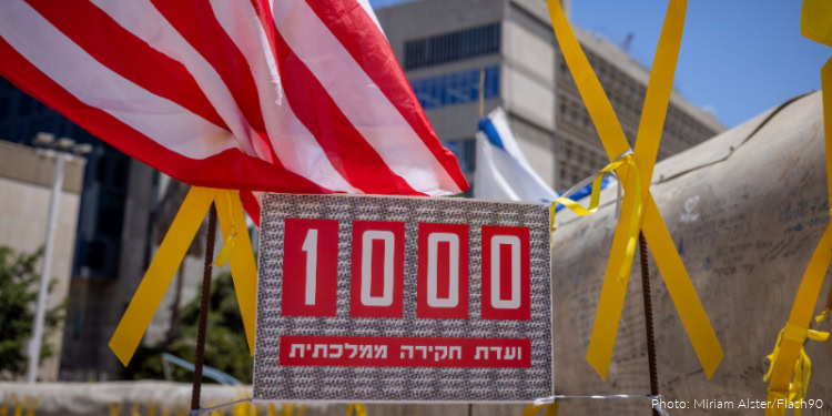 Commemorative display with American flag and yellow ribbons marking 1,000 days since October 7, in an urban setting.