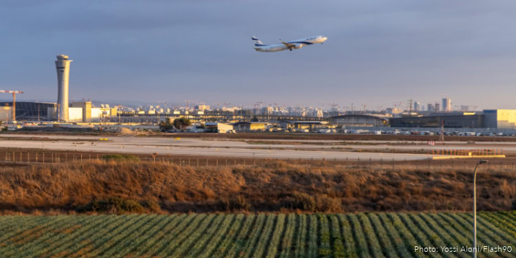 Passenger airplane taking off from runway at airport with city skyline in background during daytime.