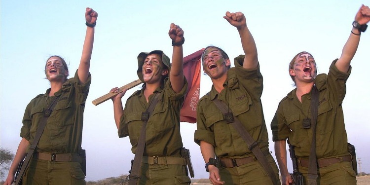 Four female soldiers celebrating while in uniform.