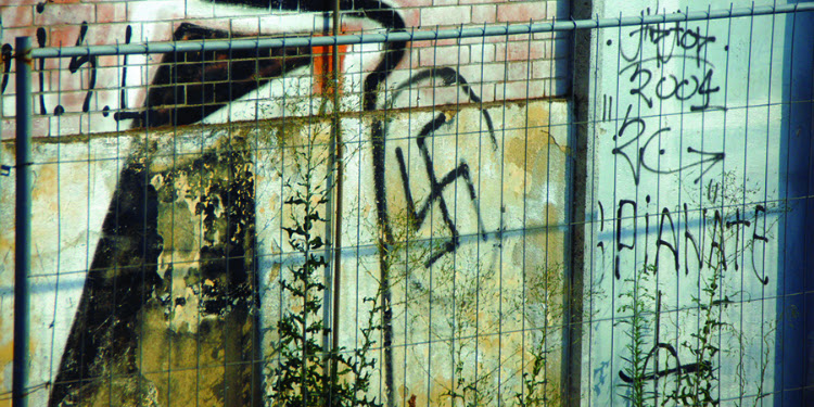 A swastika graffitied on an old building.