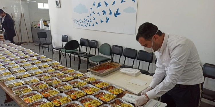 Man in a mask unpacking hot meals to give to the needy.