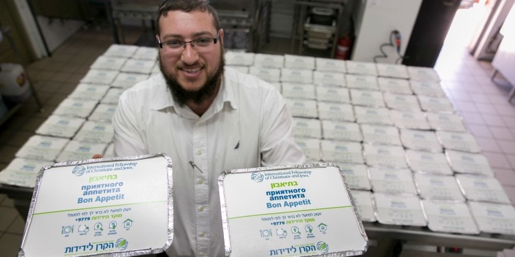 Man holding two IFCJ branded hot meals.
