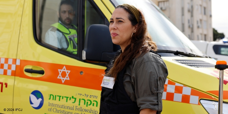 Yael Eckstein with yellow fortified ambulance which IFCJ provided to Magen David Adom. It was hit by bullets during Operation Swords of Iron.