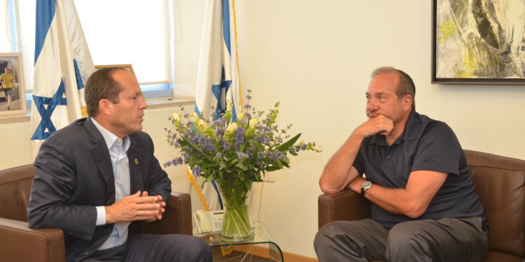 Rabbi Eckstein sitting down with Jerusalem's Mayor during an interview with Israeli flags behind them.
