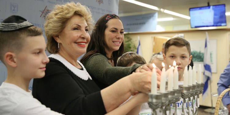 Yael Eckstein and olim lighting menorah