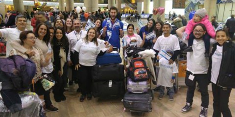 Group of Venezuelans that have just made Aliyah, many wearing IFCJ branded shirts and waving Israeli flags.