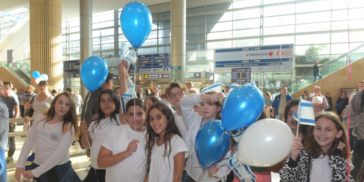 Children holding blue and white balloons just coming off a freedom flight.