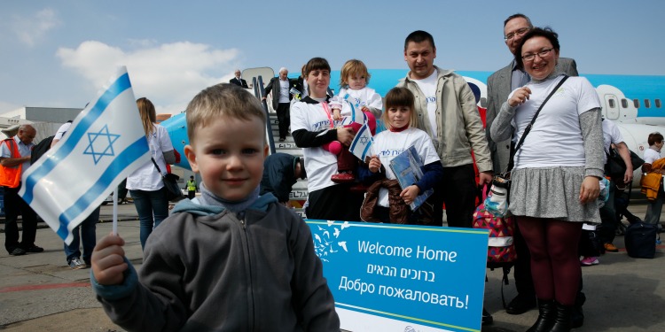 Young boy holding an Israeli flag as his family is behind him in IFCJ branded shirts.