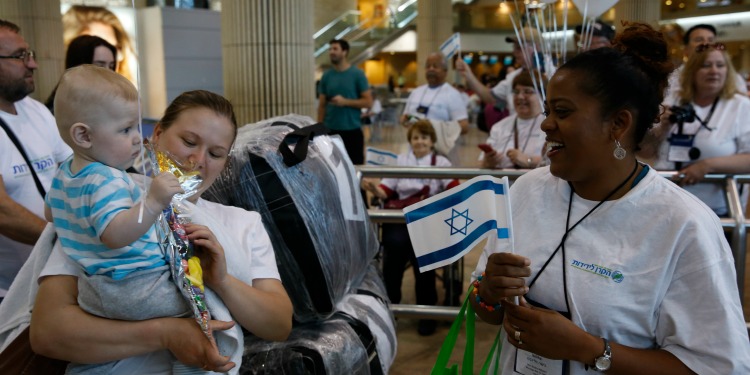 A woman holding a baby facing a smiling woman in an IFCJ branded shirt.