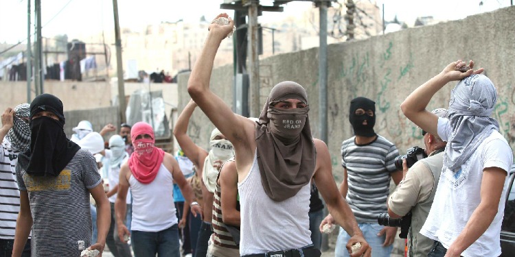 Several young men in face masks holding rocks in their hands.