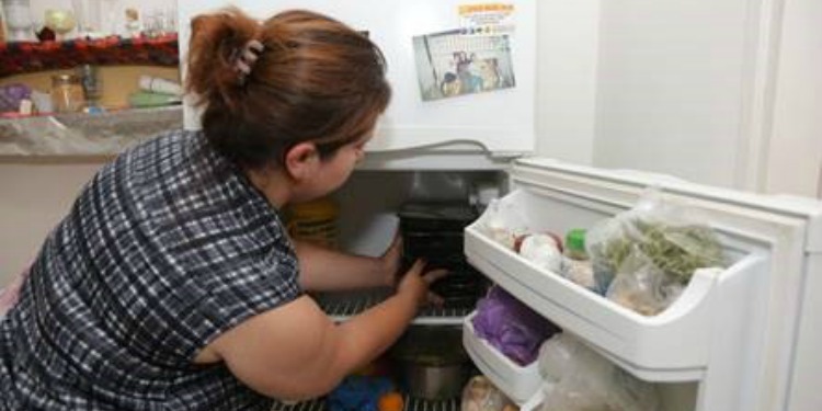 A woman putting food into a fridge.