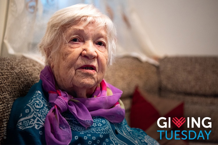 Give to IFCJ on Giving Tuesday, November 29th. Elderly Jewish woman wearing scarf. next to Giving Tuesday logo.