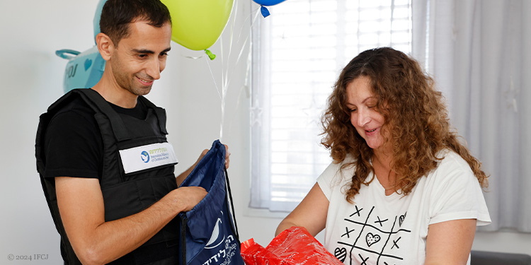 Gadi Dan (IFCJ Staff) presenting baby gift to woman