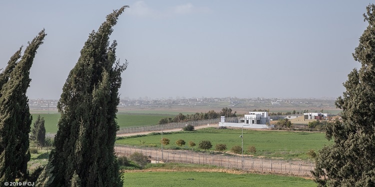 View of greenery, white buildings, and dirt road.