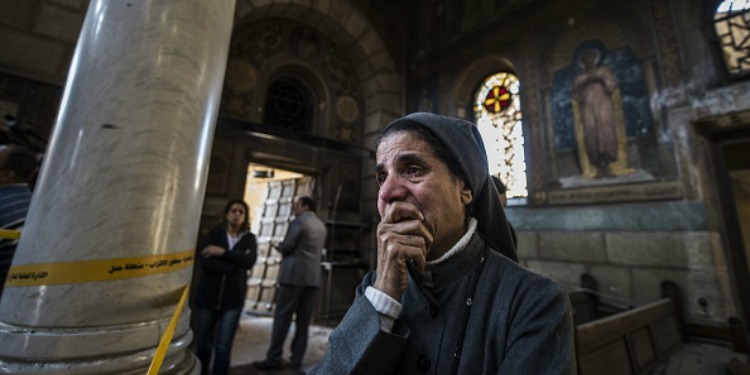 A woman holding her hand up to her mouth while crying standing inside a church.