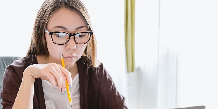 Girl with a pencil to her face, thinking.