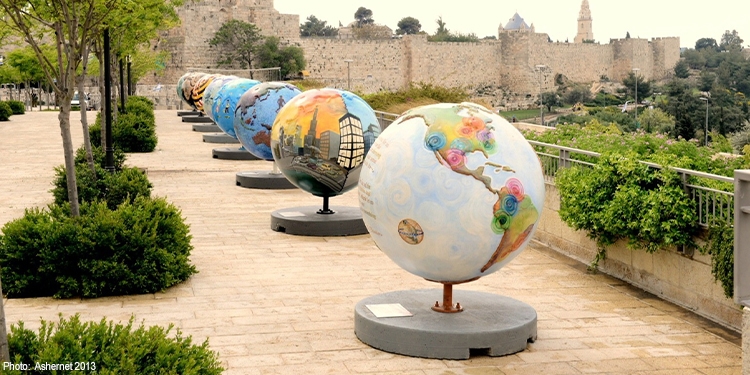 Several differently designed globes lined up in a courtyard.