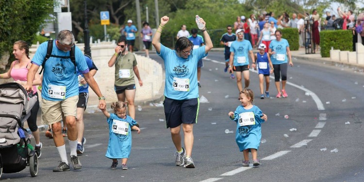 Mother and father running a race with their two young daughters.