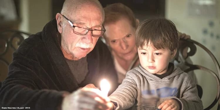 Grandparents and grandson light the menorah at Hanukkah.