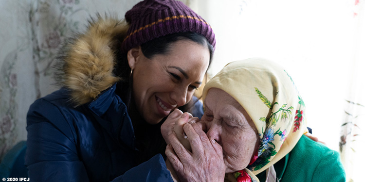 Yael Eckstein smiling at elderly Jewish woman who's kissing her hand.