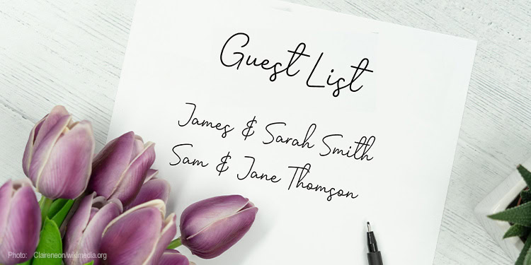 Close-up of a handwritten guest list on a notepad with purple tulips beside it, representing an organized event planning scene at IFCJ.