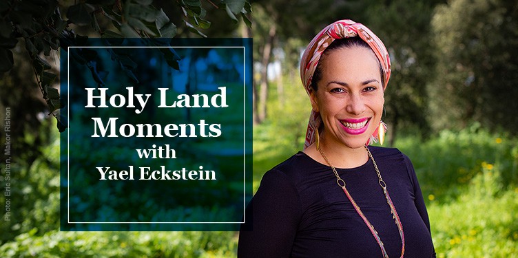Yael Eckstein stands in a wooded area wearing a red head covering. Text on images says Holy Land Moments with Yael Eckstein.