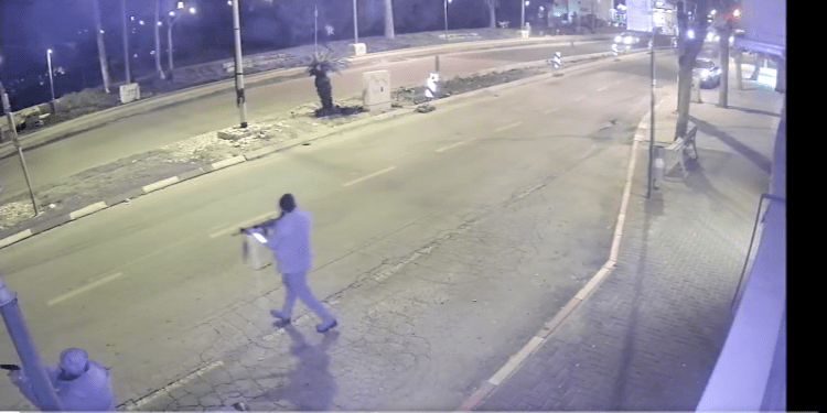 Video camera image of 2 people in the street at nights with guns.