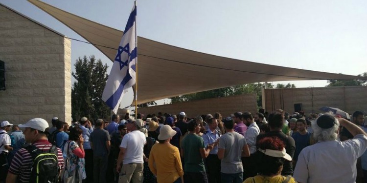 Large crowd gathered around an Israeli flag.