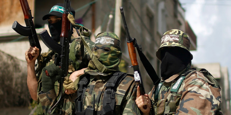 Three Hama militants in uniform holding weapons.