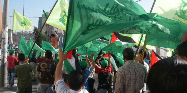 A march in Gaza with several people waving flags.