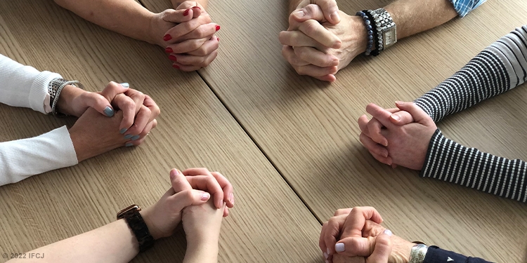 Six pairs of prayer hands in a circle.