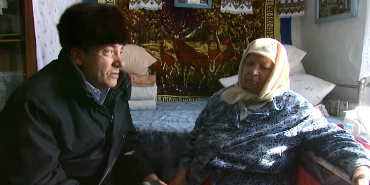 Rabbi Eckstein sitting with an elderly Jewish woman in her home.