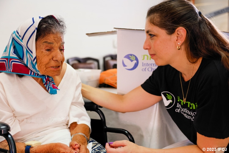 Elderly Jewish woman sitting with and talking to a Fellowship worker.