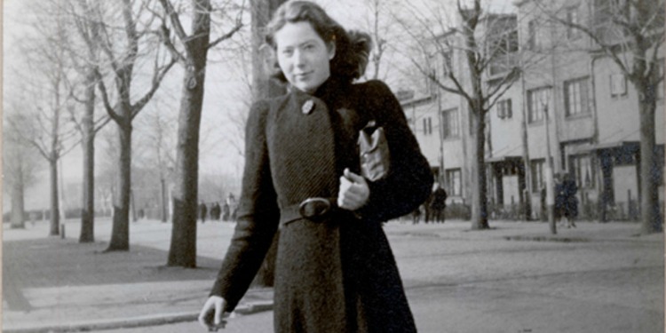 Black and white image of a young woman walking down the street.