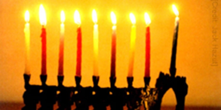 A lit menorah against an orange background.