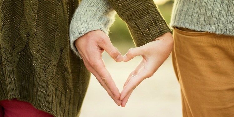 Two people making a heart shape with their hands.