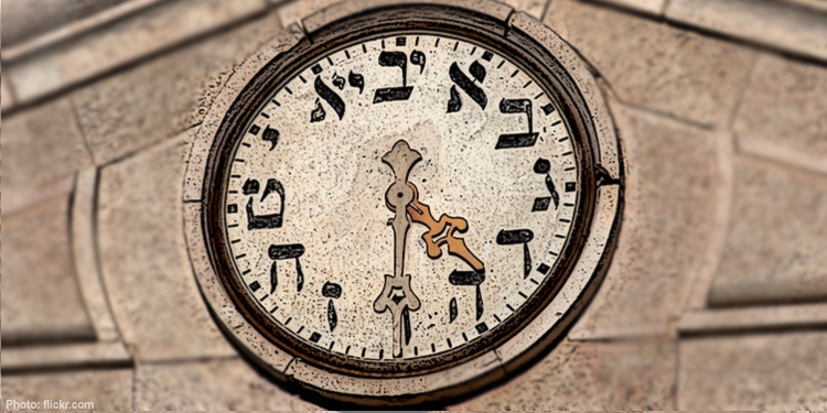Clock face on a building with the numbers written in Hebrew.