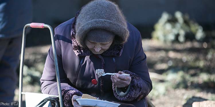 Elderly needy Jewish woman eating soup